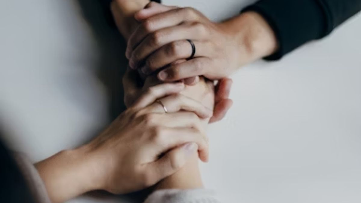 Three hands joined together on a white table, symbolizing trust, unity, and commitment.