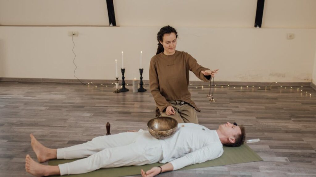 A female therapist guides a male patient through sound therapy, incorporating breathwork and meditation.