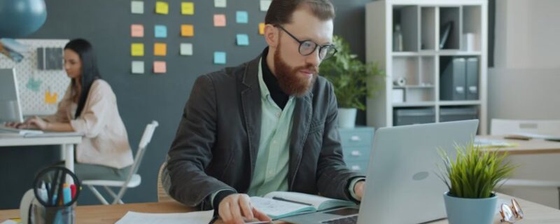 A bearded male professional works intently on his computer, showing focus and determination during addiction recovery.